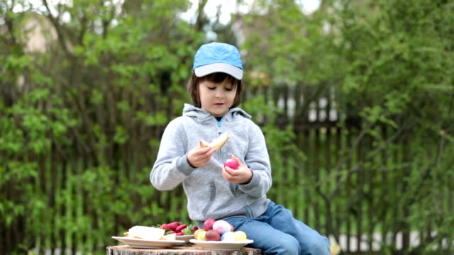 Cute-child,-having-fun-with-easter-eggs-in-the-park,-eating-sweet-bread
