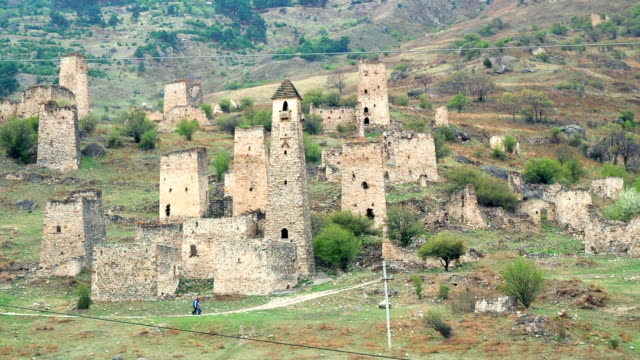 Vista-Torres-y-torres-defensivas-del-Cáucaso-del-norte.-Históricos-monumentales-edificios-medievales-en-las-montañas.-Personas-caminando-cerca-de-lugares-de-interés-históricos-en-Ingushetia