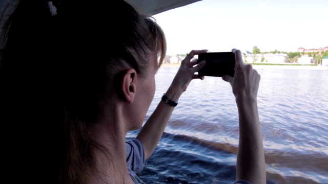 Chica-lanza-video-en-la-cámara-del-teléfono-durante-el-viaje-en-el-barco-en-el-río