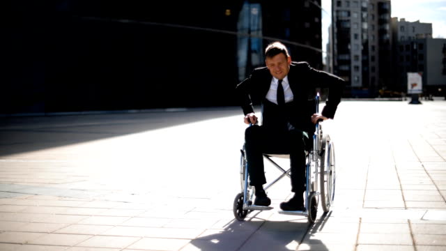 Disabled-businessman-trying-to-get-up-from-wheelchair-outside
