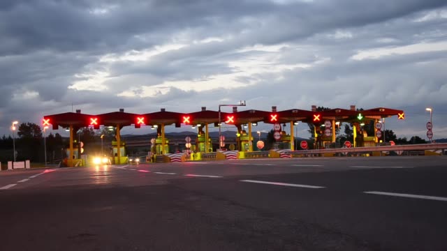 Time-lapse-of-Highway-Car-Paytoll-at-sunrise,-Night-lights-and-Autos-passing-through-toll-booths,-pay-for-using-highway-and-motorway