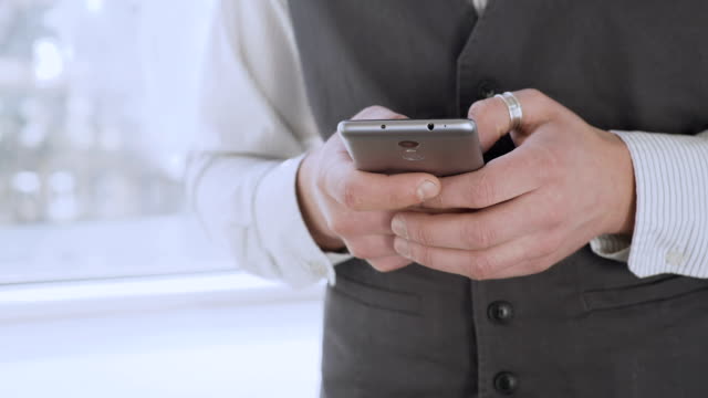 Smartly-dressed-man-holding-smartphone-in-hands,-scrolling-social-media-newsfeed