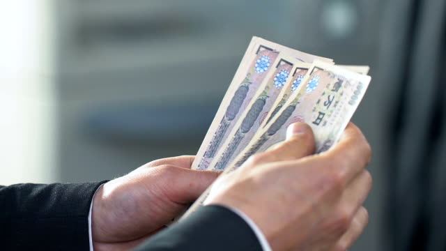 Male-hands-counting-money,-exchanging-Japanese-yen-at-bank-branch,-finance