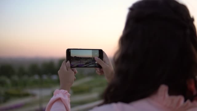 A-girl-with-long-hair-takes-a-photo-of-the-city-using-a-smartphone.-slow-motion