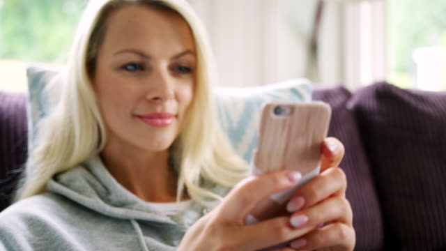 Schönen-lächelnden-blonden-Frau-im-Hause-mit-Handy