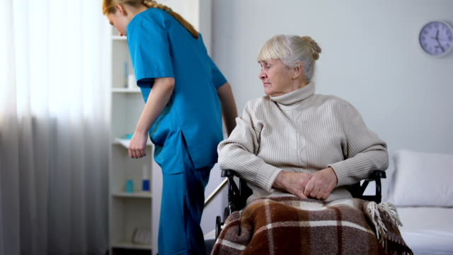 Portero-de-hospital-grosero-limpieza-de-habitación,-mover-la-silla-de-ruedas-con-viejo-paciente-femenino