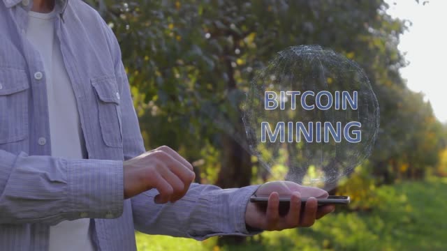 Unrecognizable-man-shows-conceptual-hologram-with-text-Bitcoin-Mining