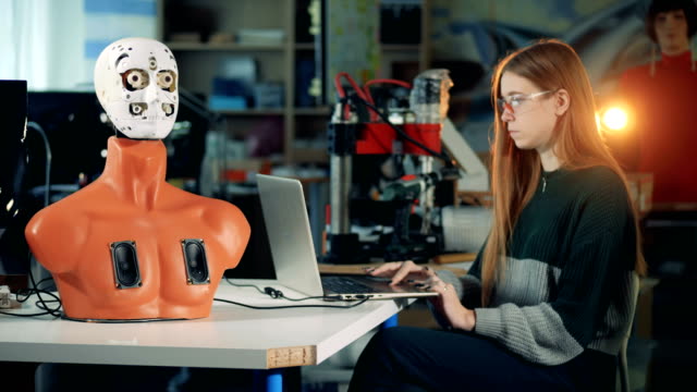 Wissenschaftler-Robotik-arbeitet-mit-einem-Laptop,-einen-Roboter-zu-steuern.-Ingenieur-mit-futuristischen-humanoid,-Cyborg-zu-arbeiten.