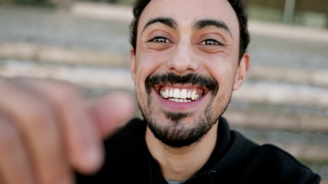 Hombre-árabe-teniendo-video-chat-fuera,-agitando-la-mano
