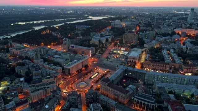 Vista-aérea-de-Maidan-Nezalezhnosti-en-Kyiv-(Kiev),-Ucrania-y-el-río-Dnieper-durante-la-puesta-de-sol-por-la-noche.-El-monumento-de-la-independencia-se-ve-en-la-parte-central-de-la-imagen