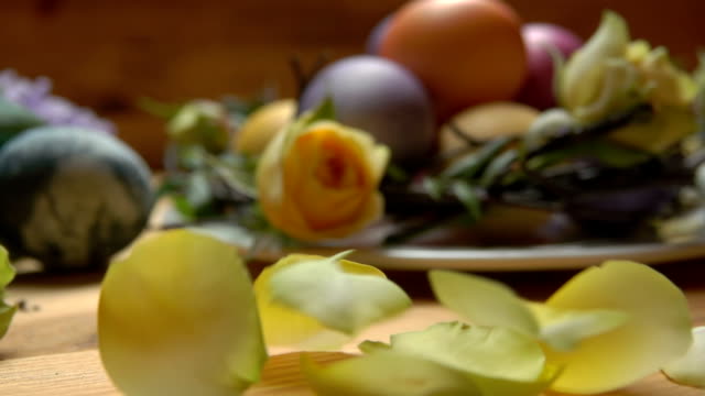 Die-Blütenblätter-der-gelben-Rose-fallen-auf-den-Tisch-mit-den-Ostereiern
