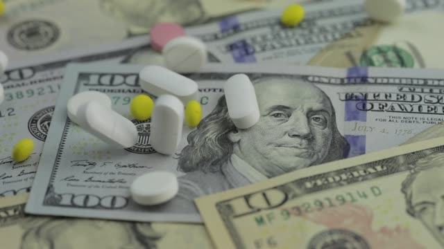 Pills-falling-on-dollar-banknotes,-expensive-medication,-pharmaceutical-business