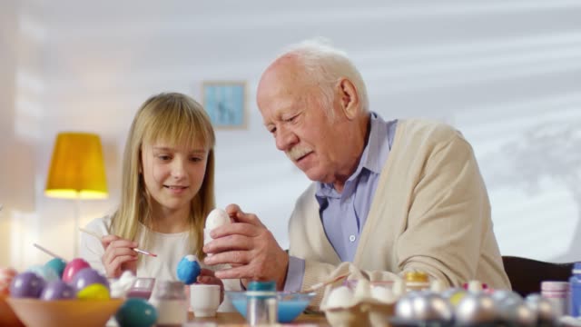 Abuelo-enseñando-nieta-para-decorar-huevos