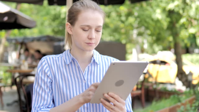 Mujer-joven-usando-la-tableta,-sentado-en-Cafe-Terrace
