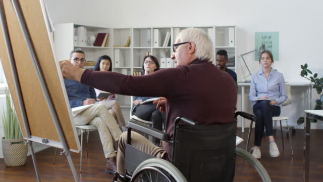 Estudiantes-multiétnicos-escuchando-al-profesor-discapacitado