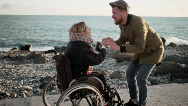 Mann-belebt-seine-geliebte-Frau-im-Rollstuhl-im-Meer-Strand-sitzen