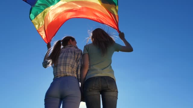 Junge-Lesben-mit-Flagge-stehen-im-Freien