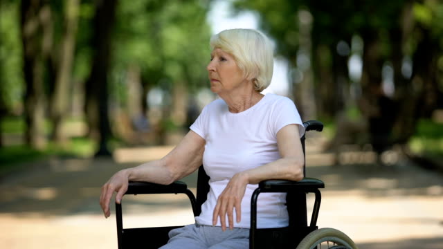 Depressive-ältere-Frau-sitzt-im-Rollstuhl-im-Reha-Center-Park