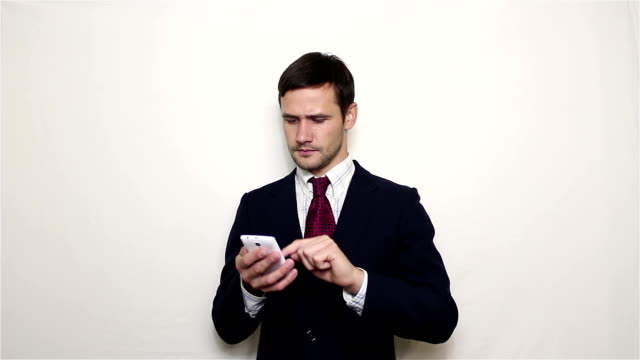 Der-junge-hübsche-Geschäftsmann-zieht-sein-Smartphone-aus-der-Tasche-und-schaut-durch-den-Newsfeed.