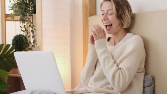 Frau-lacht,-während-sie-Laptop-im-Bett-verwendet