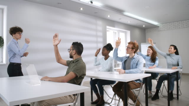 Diverse-Group-of-College-Students-Listening-to-Teacher-and-Raising-Hands