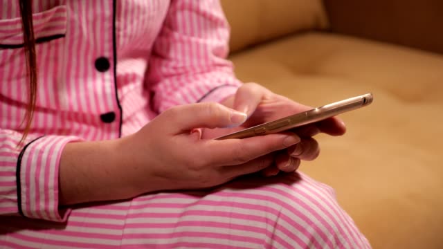 phone-is-in-the-hands-of-a-woman-in-pink-pajamas.