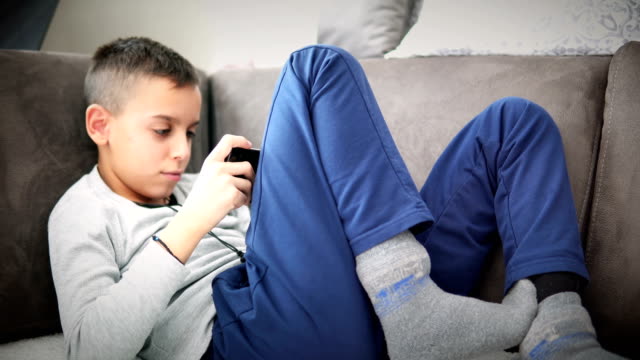 Boy-sits-on-sofa-plays-video-games-with-smartphone