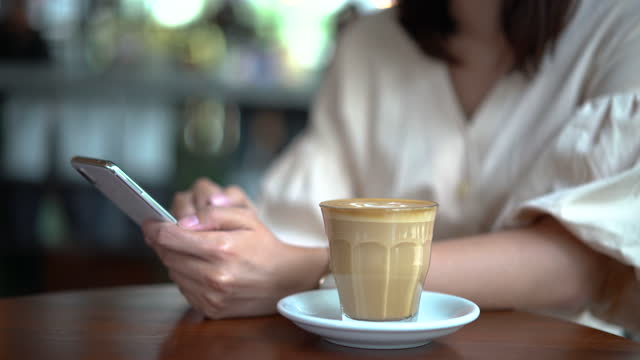 Junge-asiatische-Frau-mit-Smartphone-im-Café