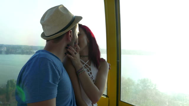 Hermosa-mujer-besando-a-su-novio-en-teleférico-a-la-orilla-del-mar