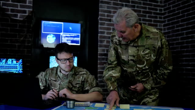 chief-and-soldier-in-camouflage-uniform,-at-briefing,-in-monitoring