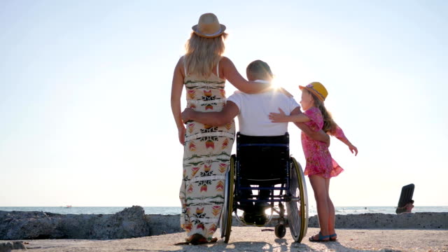 spouse-in-wheel-chair-hug-wife-and-little-girl-in-backlight