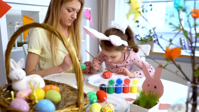 Frohe-Ostern!-Mutter-und-ihre-kleine-Tochter-tragen-lustige-Hasenohren-Ostereier-färben
