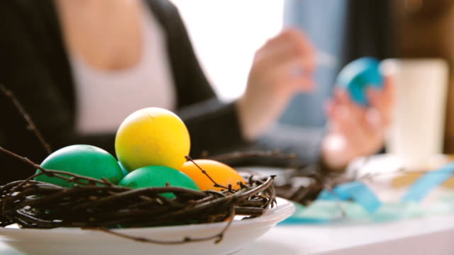 Ostern,-Feiertage,-Tradition-und-Konzept---Nahaufnahme-von-Frau-Hände-Ostereier-färben-mit-Farben-und-Pinsel.-Happy-Easter-Konzept