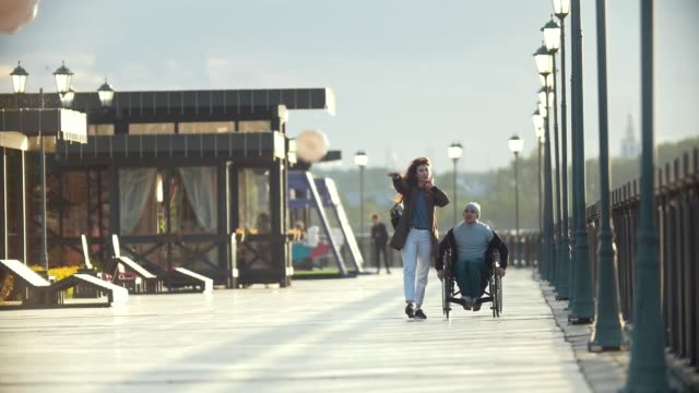 Behinderte-Menschen-im-Rollstuhl-am-Telefon-gehen-gemeinsam-ihre-Freundin-auf-dem-Kai