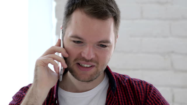 Young-Man-Talking-on-Phone-in-Loft-Workplace