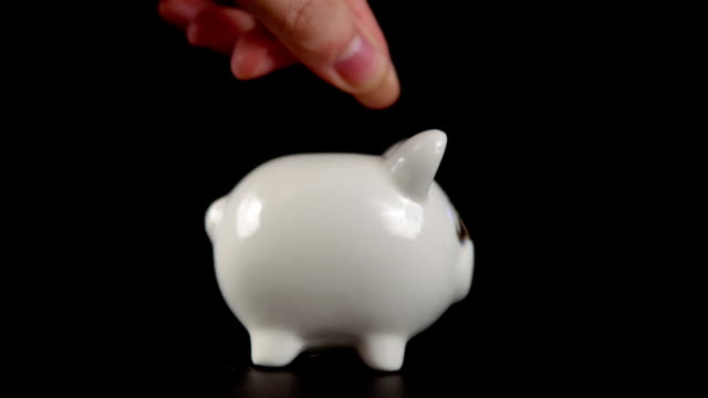 The-concept-of-charity-during-the-movember,-someone-puts-a-coin-in-piggy-bank.