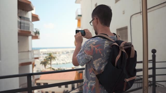 Guy-is-taking-photo-of-amazing-view-from-balcony-using-camera-of-mobile-phone