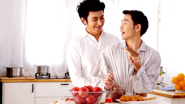 Happy-gay-couple-sweet-at-home-kitchen.-Man-cooking-breakfast-for-him-boyfriend-with-attractive-smiling.-People-with-gay,-homosexual,-relationship-concept.