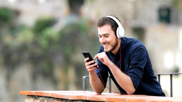 Hombre-feliz-escuchando-música-del-teléfono-en-un-balcón