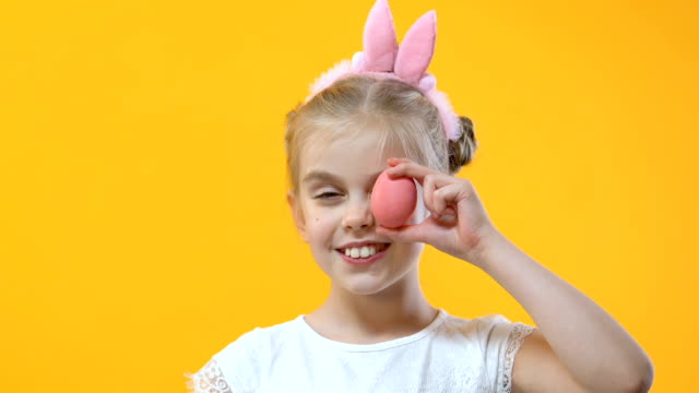 Adorable-child-having-fun-holding-colored-egg-near-eye,-perfect-Easter-mood