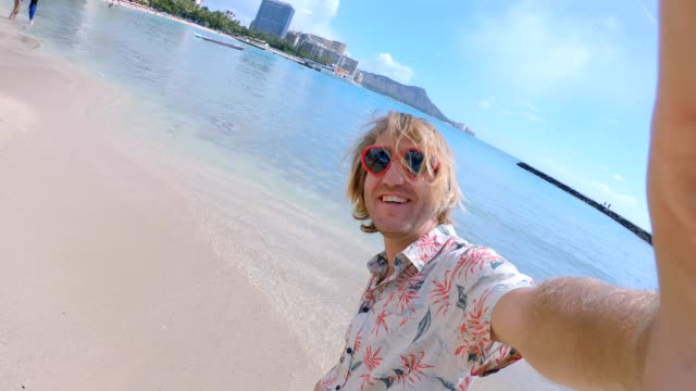 Junger-Mann-mit-Herz-Form-rot-Sonnenbrille-Selfie-Aufnahme-am-Strand-von-Waikiki-in-Honolulu-Hawaii