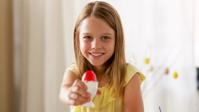 Chica-feliz-mostrando-color-huevo-de-Pascua-en-casa