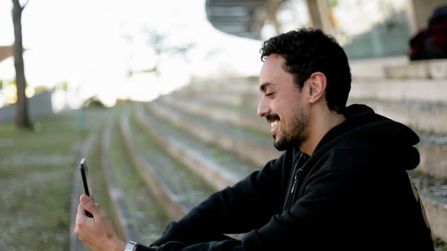 Side-view-of-Arabic-man-having-video-chat-outside,-waving-hand