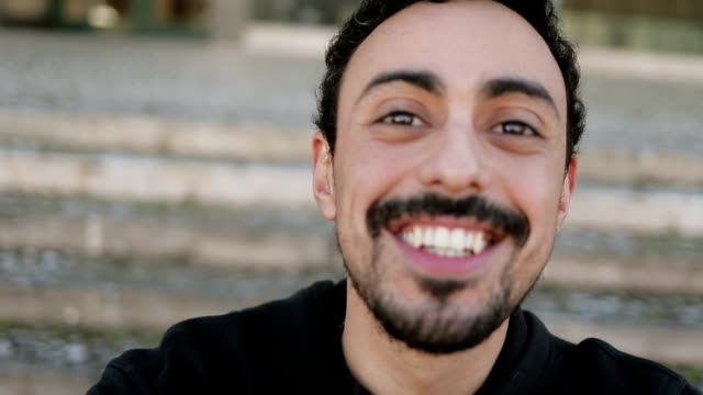 Closeup-of-Arabic-man-having-video-chat-outside,-waving-hand