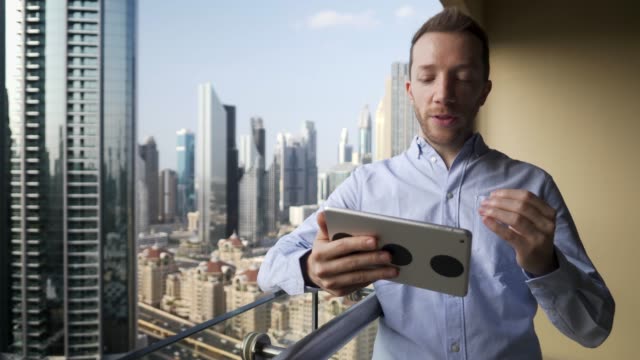 Young-man-using-tablet-to-speak-and-communicate-with-skyscraper-view-background