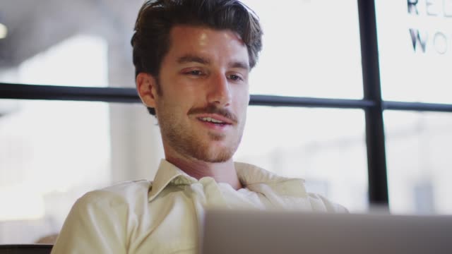 Young-white-man-working-on-a-laptop-computer,-low-angle,-head-and-shoulders
