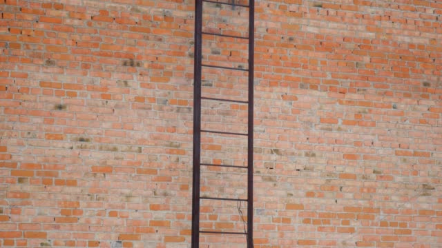 Staircase-from-metal-on-brick-wall-background.-Movement-up.-Fire-escape-hugs-facade.