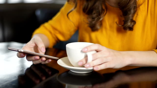 Mujer-bebiendo-café-en-café-y-usando-smartphone,-charlando-en-redes-sociales