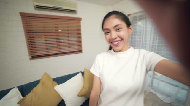 Young-Asian-teenager-woman-vlog-at-home,-female-using-smartphone-making-vlog-video-to-social-media-in-living-room.-Lifestyle-woman-relax-in-morning-at-home-concept.