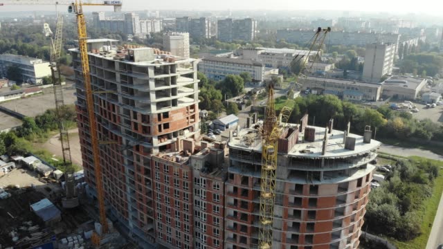 An-aerial-view-of-a-residential-building-in-construction.-Tower-cranes-working-by-the-building.-4K